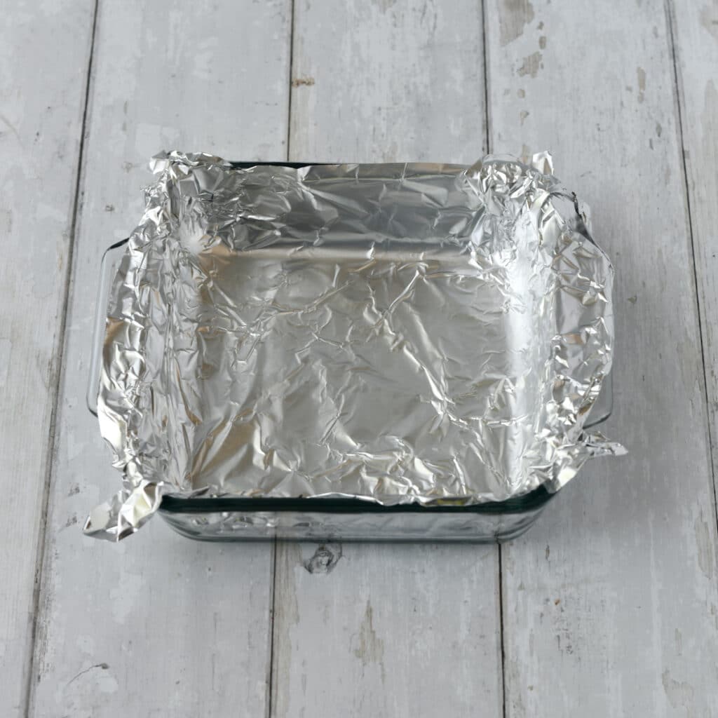 Lining a baking dish with foil.