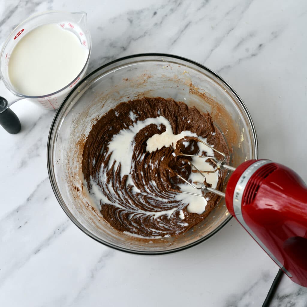 Beating milk into chocolate batter with a hand mixer.
