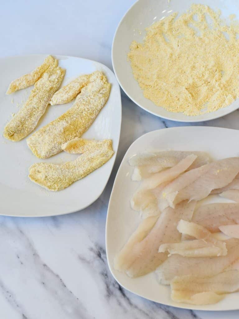 Process image of coating fish in breading before cooking.