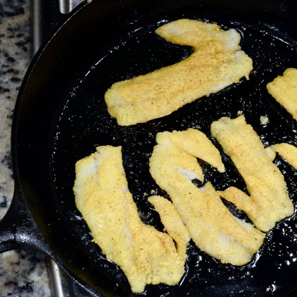 Cooking breaded pieces of fish in oil in a pan.