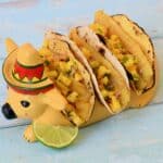 Image of fish tacos in a taco holder designed like a cow with a sombrero.