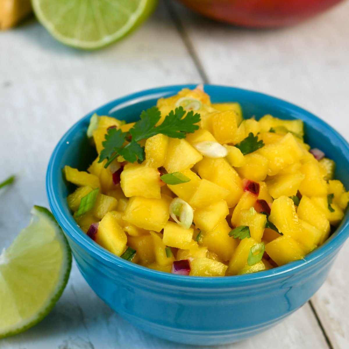 Mango salsa with lime wedge on side of bowl.
