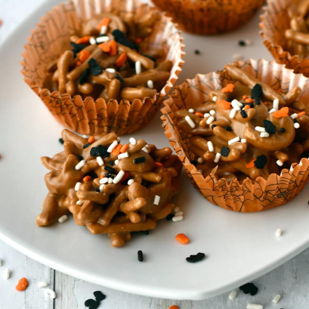 Cookie butter haystacks candy mounds with halloween sprinkles in orange cupcake liners.
