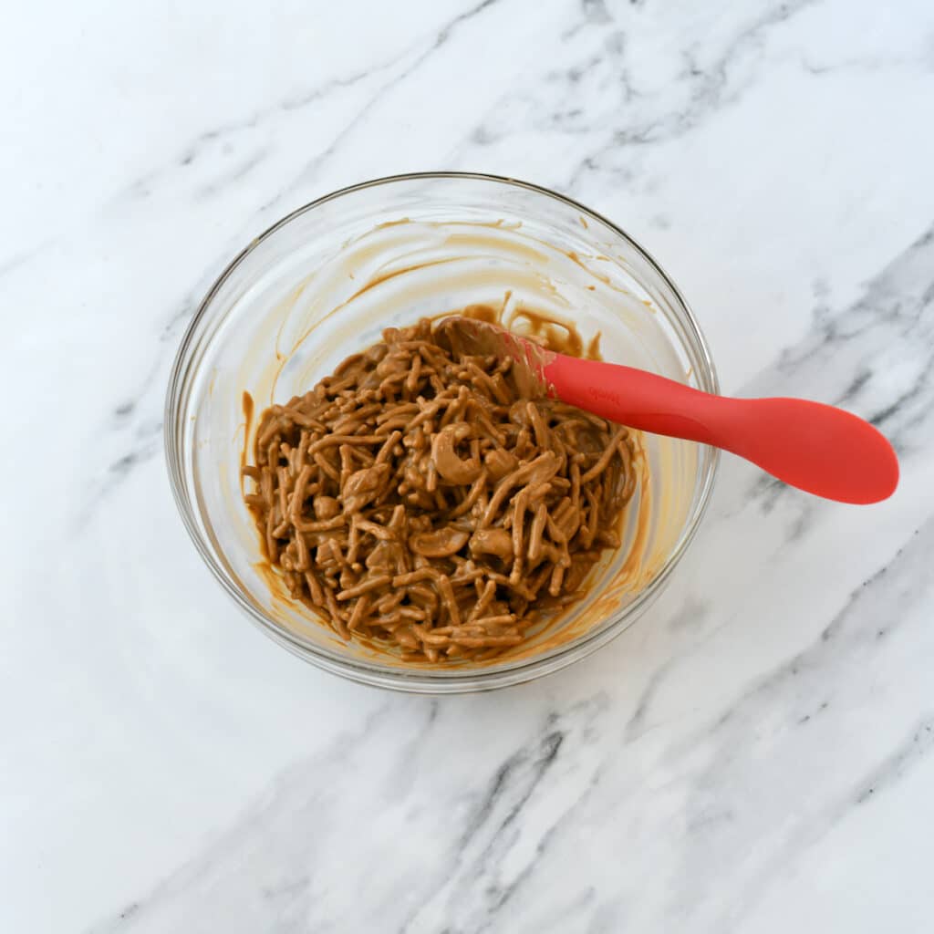 Mixture of chow mein noodles and cookie butter to make haystacks in a glass bowl.
