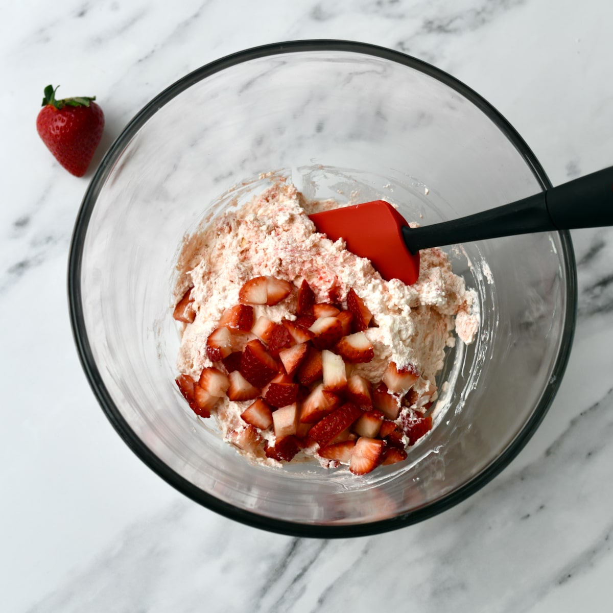 Glass bowl with cream cheese beaten and Little Debbie strawberry rolls, Cool Whip and chopped fresh strawberries.
