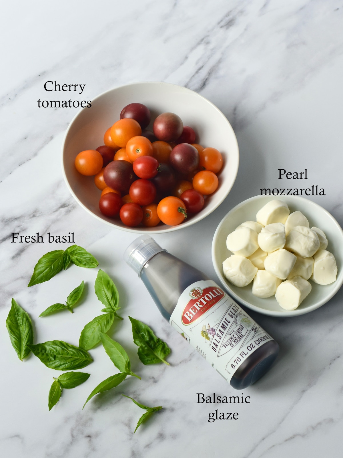 Ingredients for cherry tomato mozzarella balls basil skewers appetizers.
