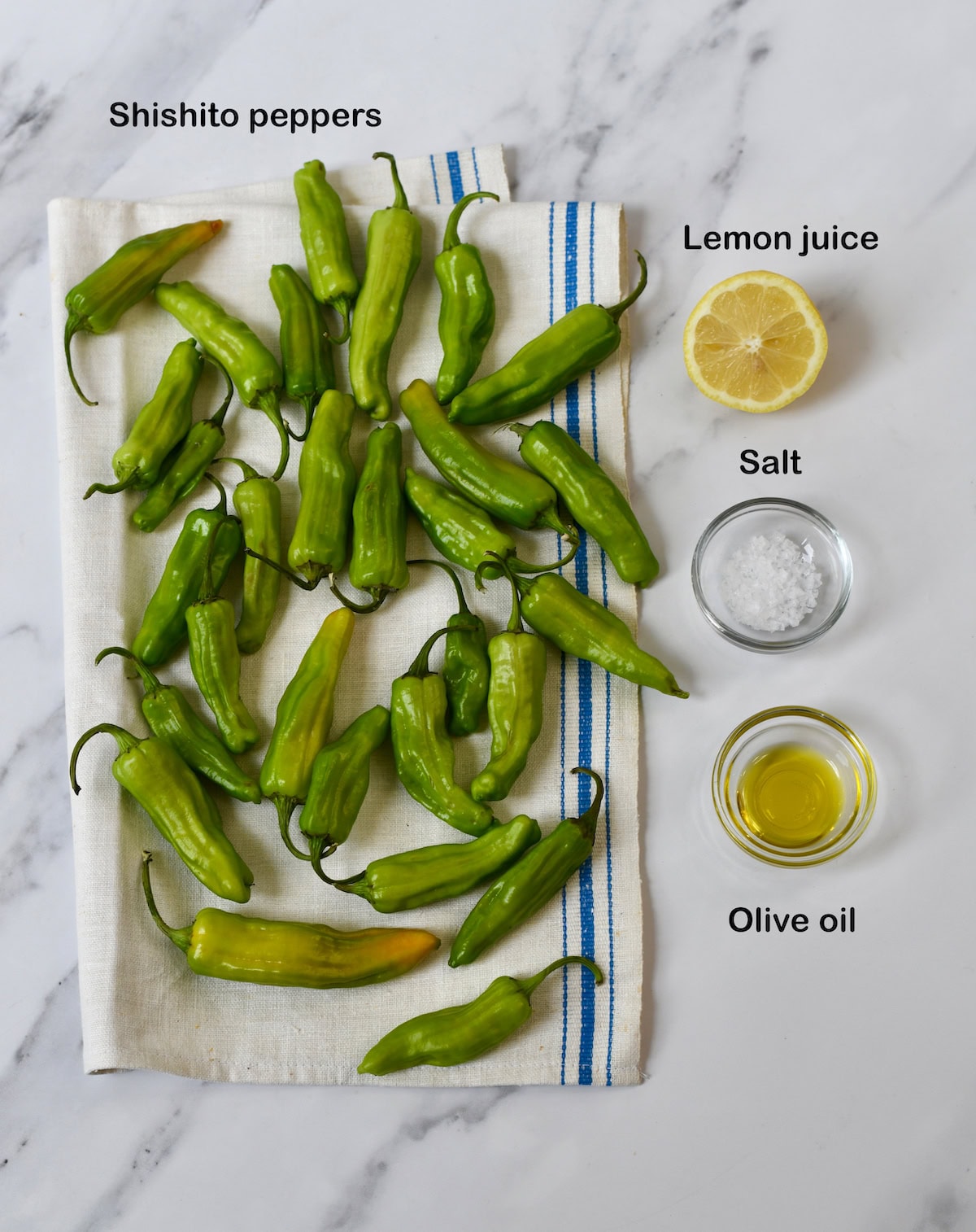 Fresh Shishito Peppers with stems on a kitchen towel. Ingredients for Blistered Shishito Peppers.