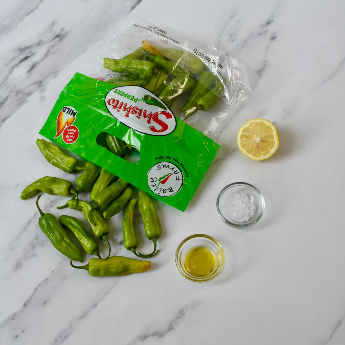Bag of fresh shishito peppers spilled out onto marble surface. Where to buy shishito peppers.