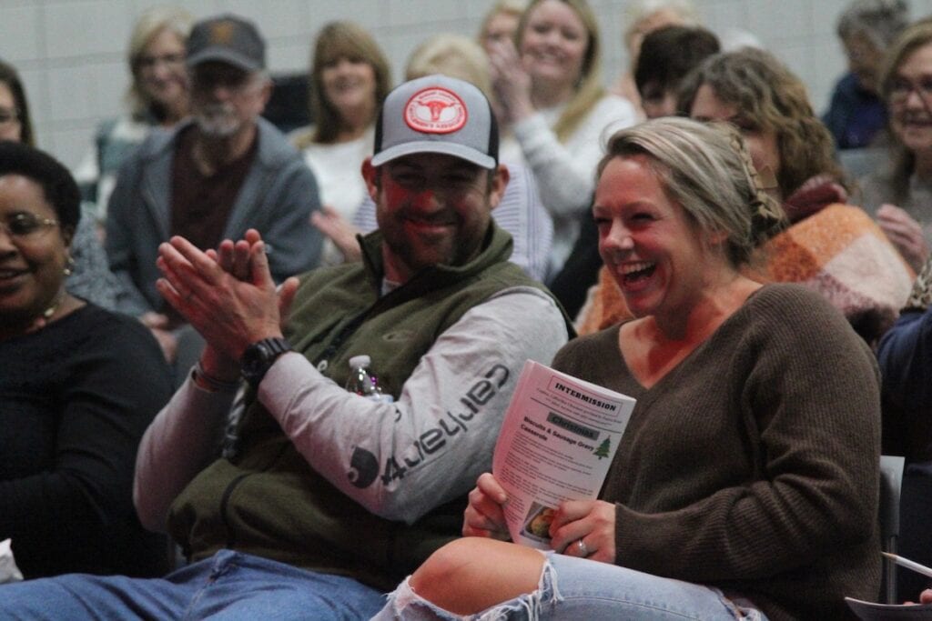 Man and woman laughing in a crowd.