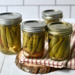 Easy Pickled okra in flour jars on red striped kitchen towel.