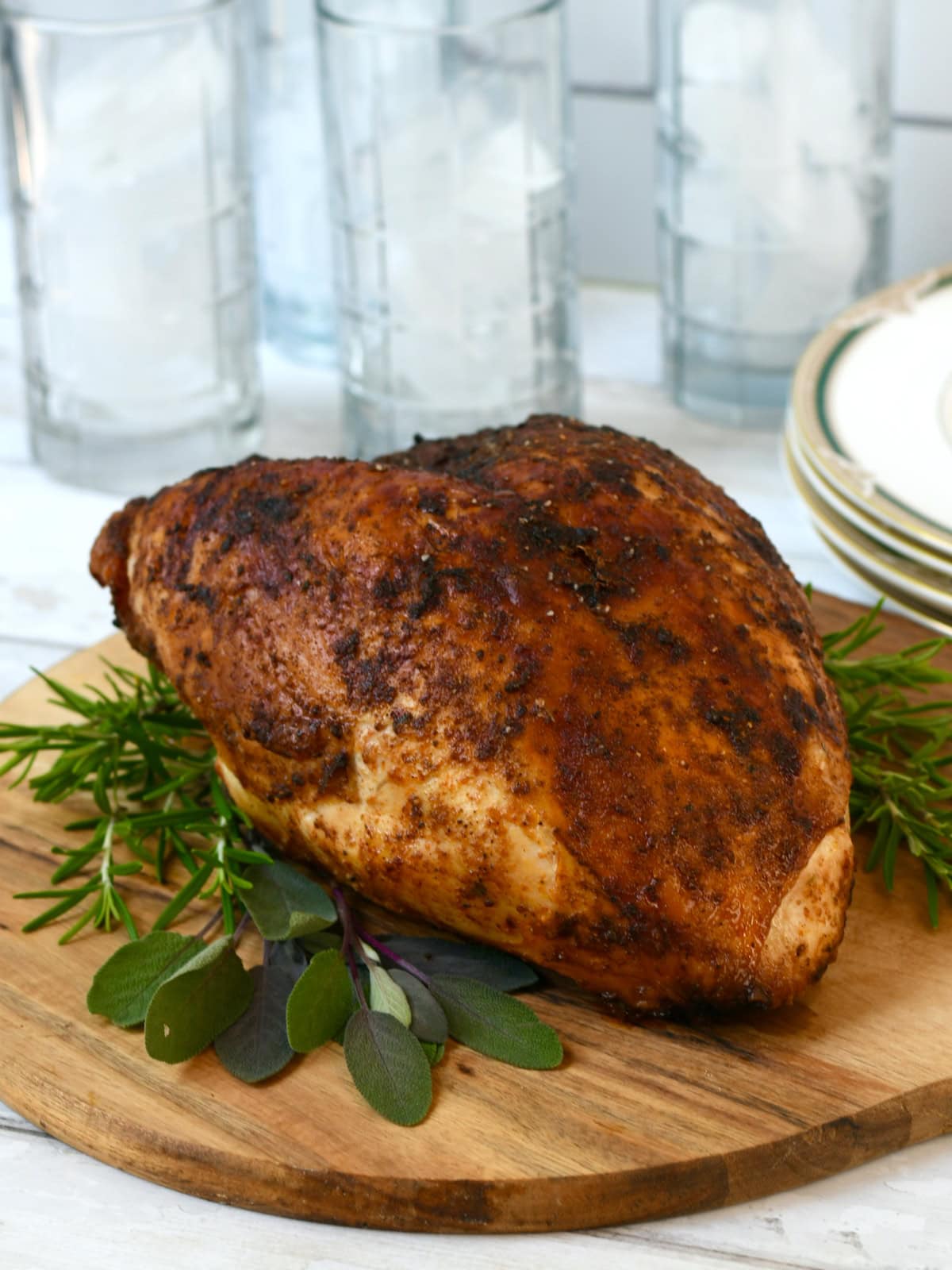 roasted turkey breast on wooden cutting board with ice in glasses background.
