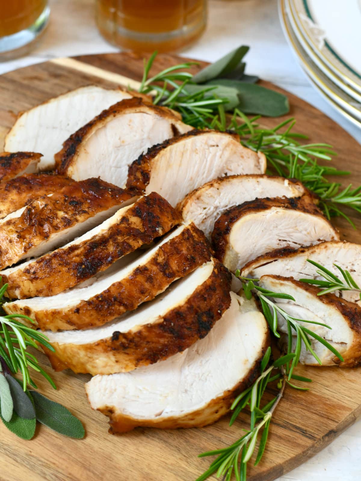 Air fryer turkey breast roast on wood platter with fresh rosemary.
