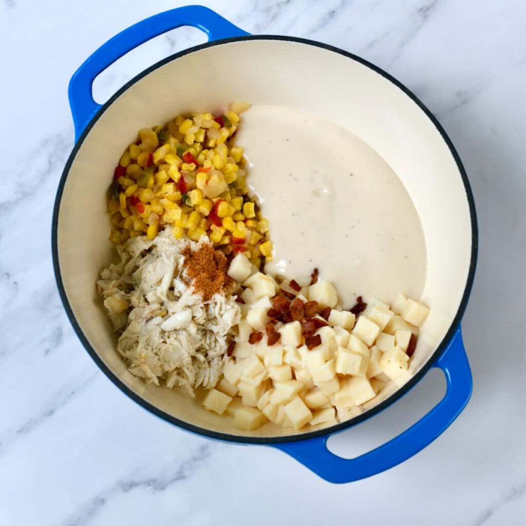 Ingredients for shortcut corn and crab soup in separate piles inside a blue pot.