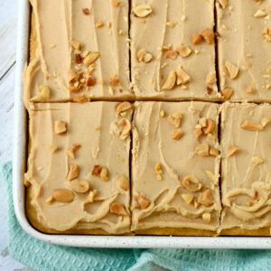 Peanut Butter Sheet Cake with cake mix scored into slices in the pan topped with chopped peanuts.