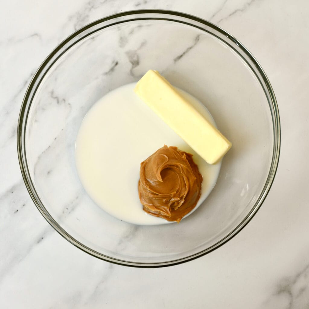 Process shot making peanut butter sheet cake: peanut butter, butter, milk in a glass bowl.
