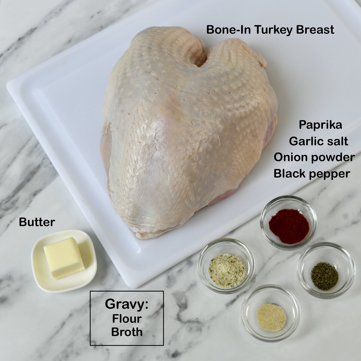 Raw turkey breast on cutting board with seasonings in bowls around it.
