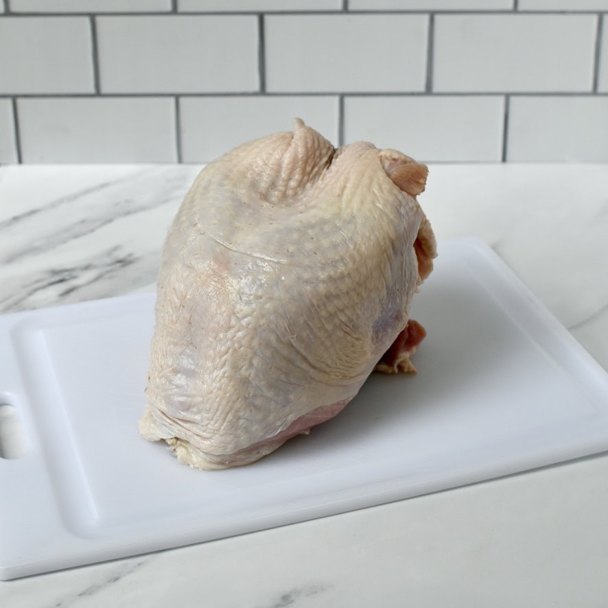 Raw turkey breast with ribs on cutting board.