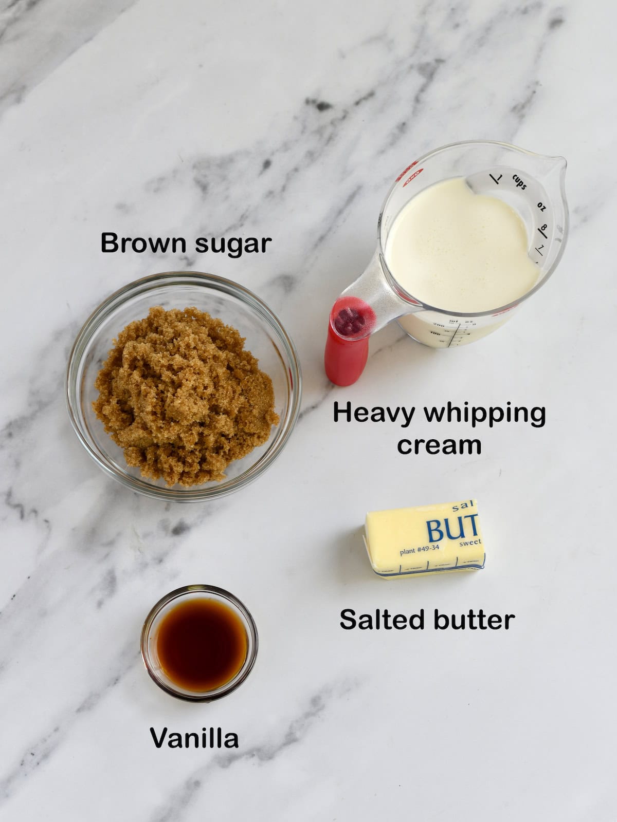 Brown sugar, butter, cream and vanilla on marble surface.
