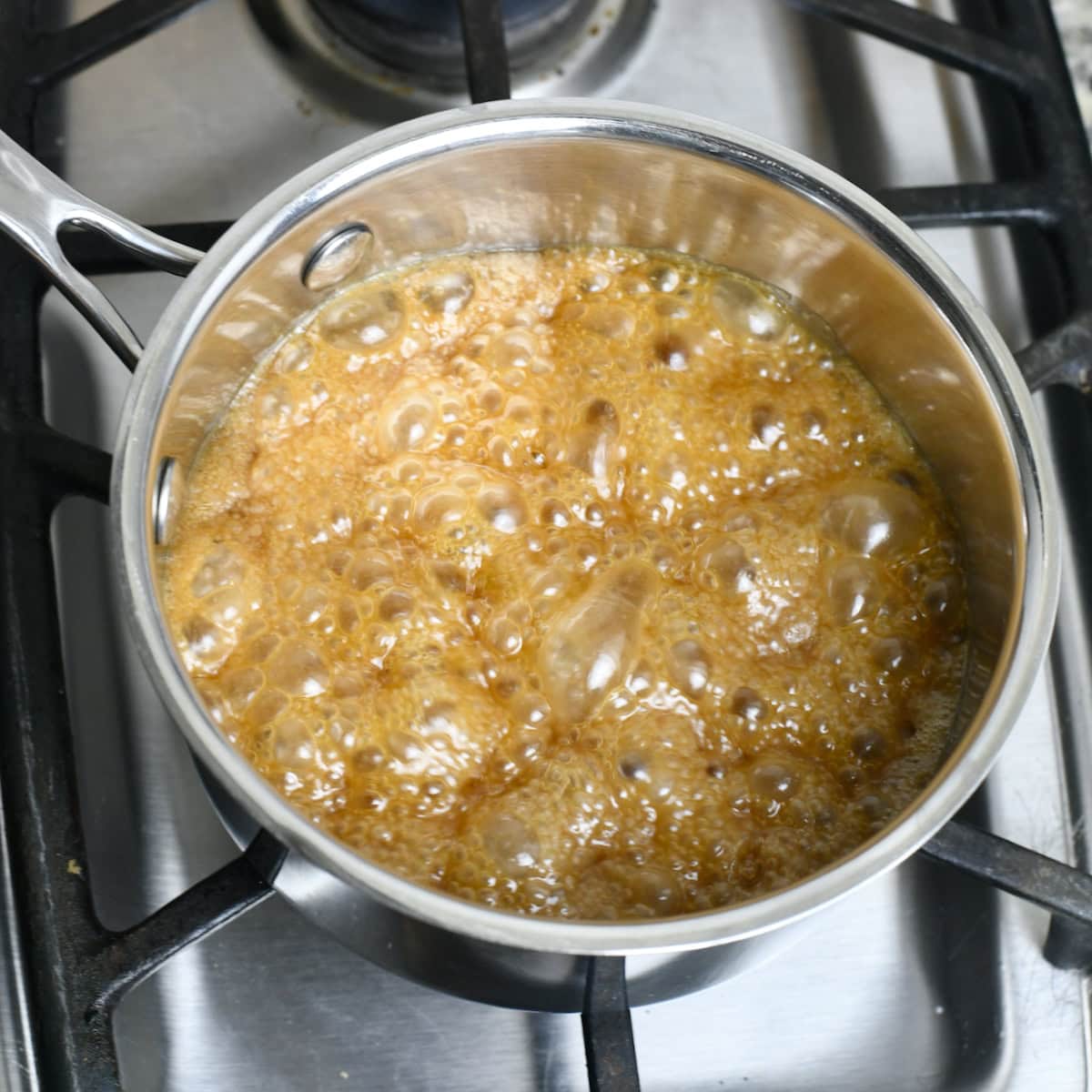 Brown sugar mixture boiling in a saucepan to make caramel glaze.
