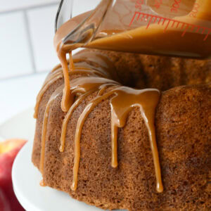 Brown sugar caramel glaze drizzling out of measuring cup onto a bundt cake.