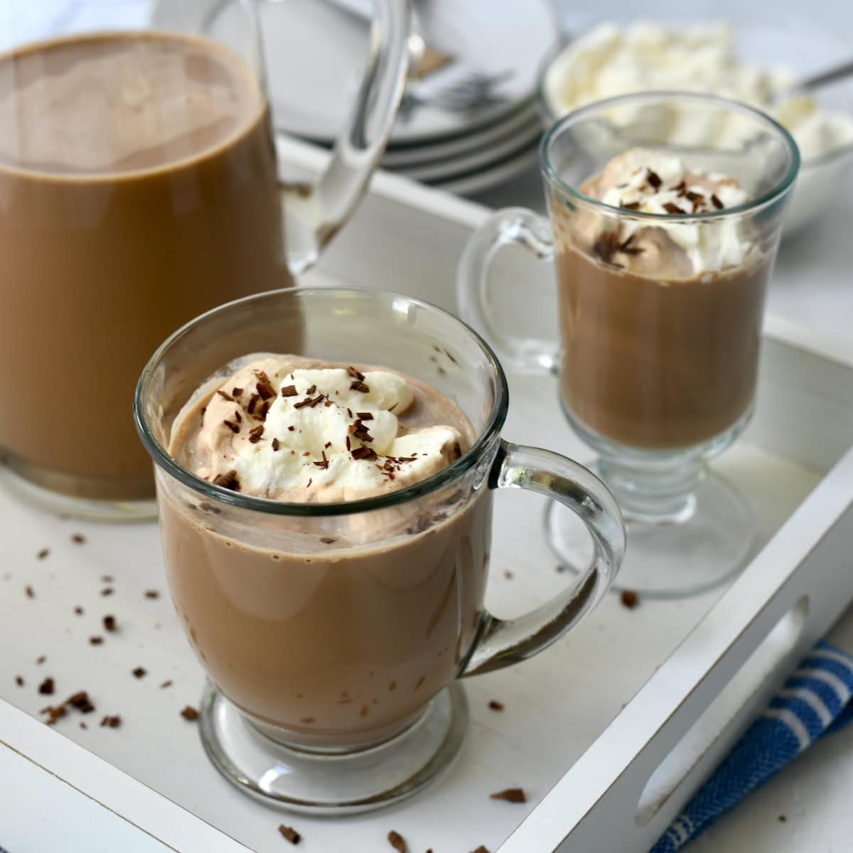 Iced Mocha punch in glass coffee mugs with whipped cream and chocolate shavings with pitcher next to them.