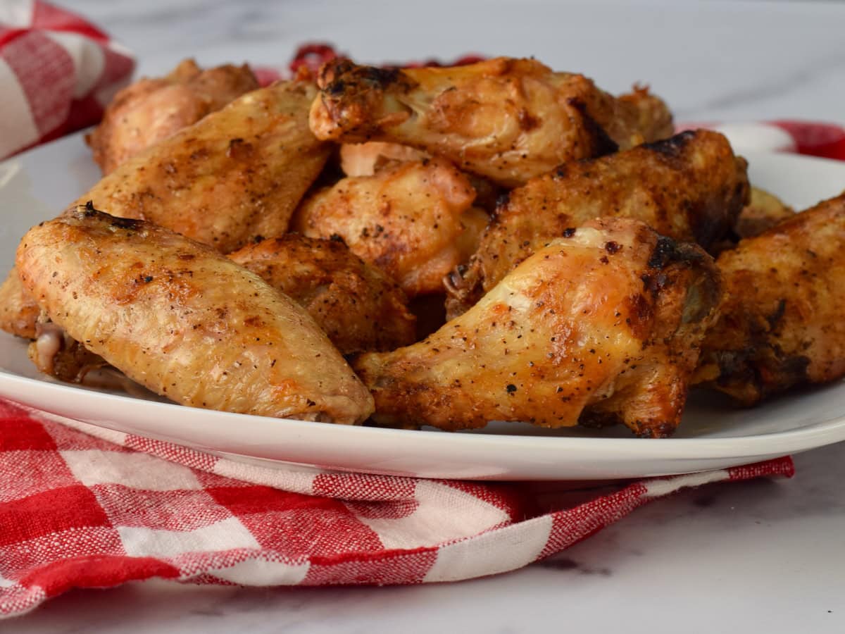 Crispy baked chicken wings on a white plate, set on a checkered tablecloth