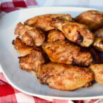 Crispy baked chicken wings on a white plate, set on a checkered tablecloth