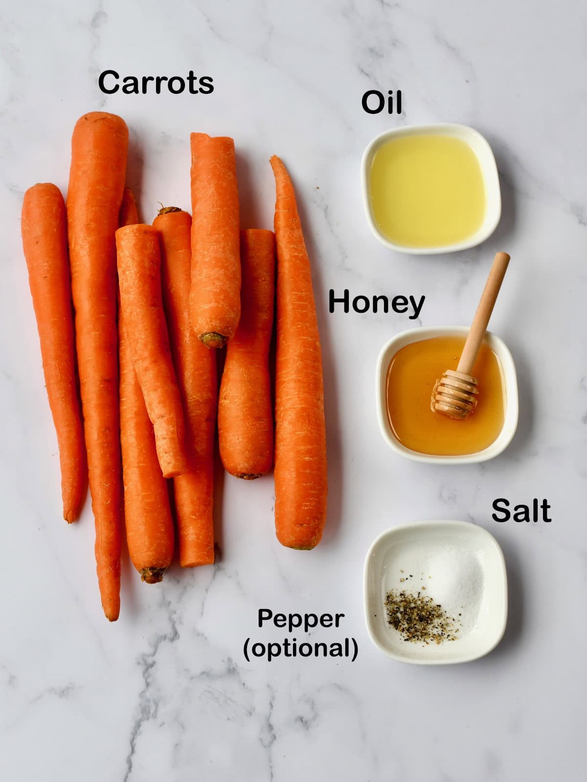 Fresh carrots, oil, honey, salt, and optional pepper arranged on a marble surface
