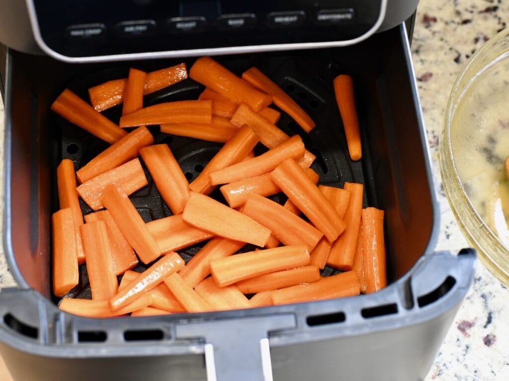 Chopped carrots placed in an air fryer basket before cooking
