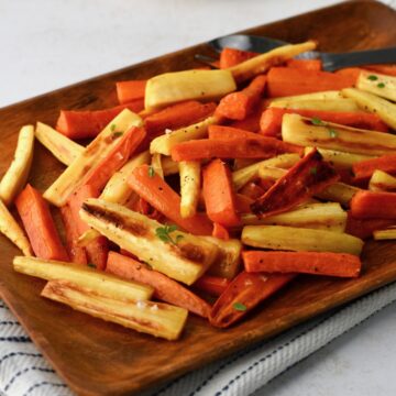 Roasted parsnips and carrots served on a wooden platter
