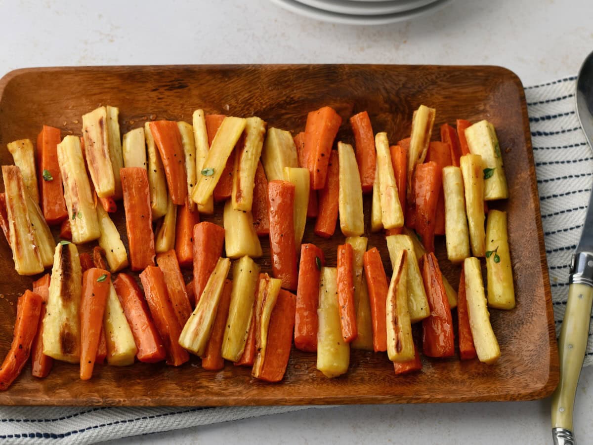 Roasted parsnips and carrots served on a wooden platter