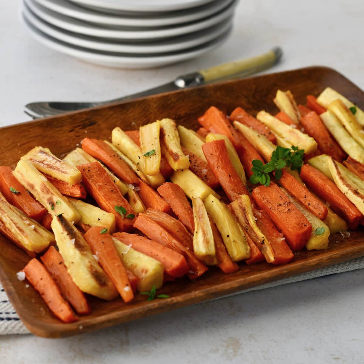 Roasted parsnips and carrots served on a wooden platter