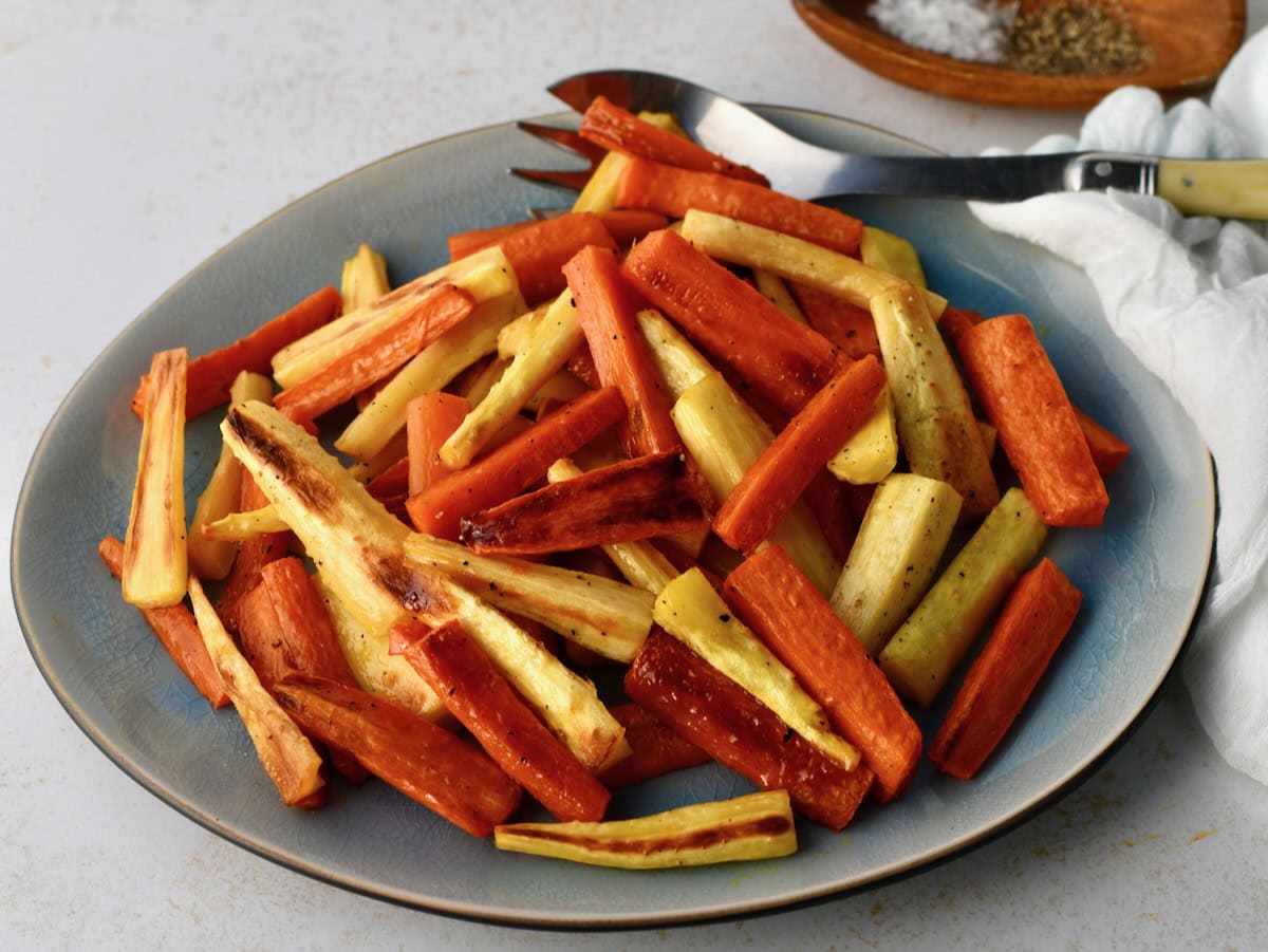 Roasted carrots and parsnips arranged on a blue plate