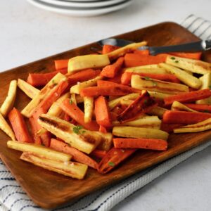 Roasted parsnips and carrots served on a wooden platter