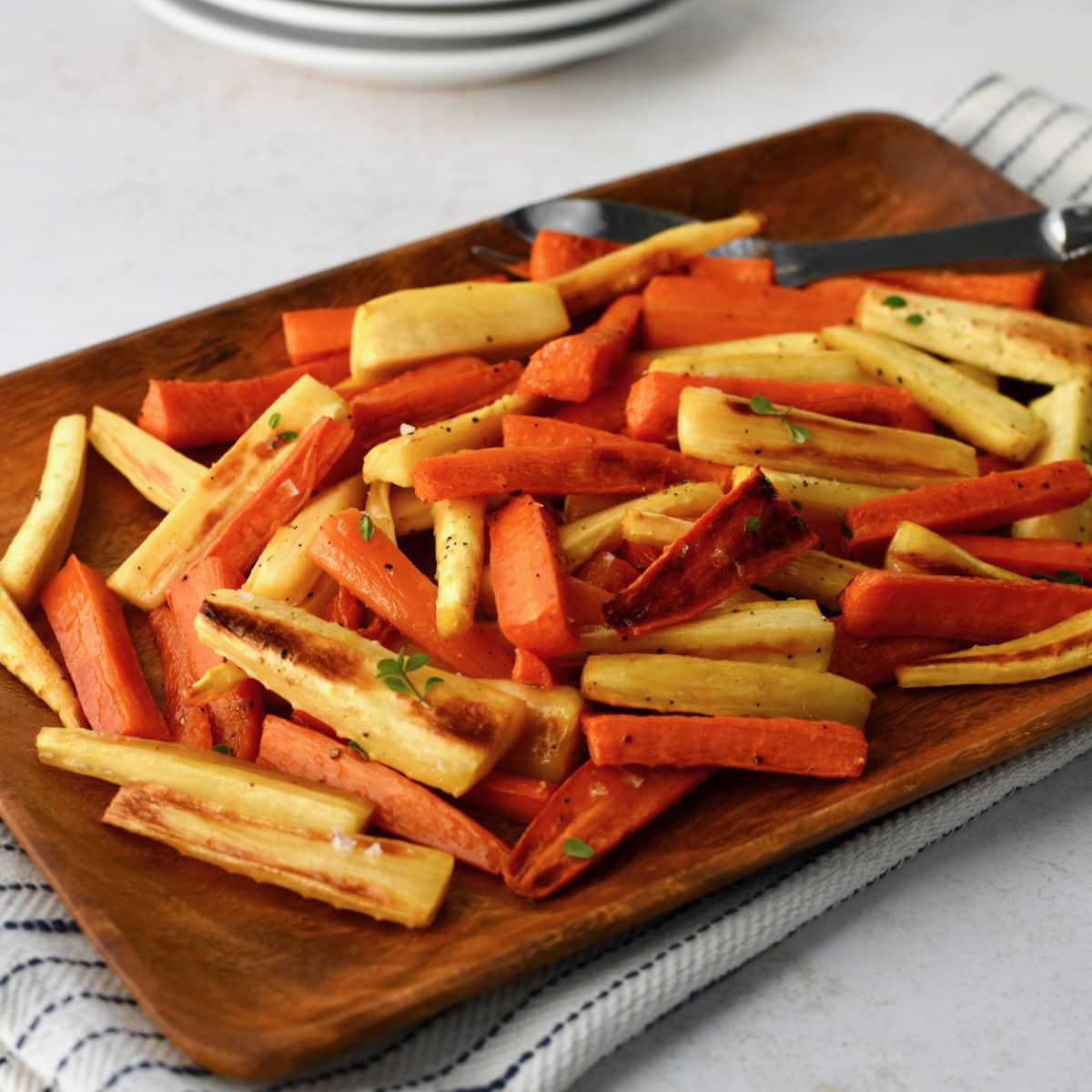 Roasted parsnips and carrots served on a wooden platter