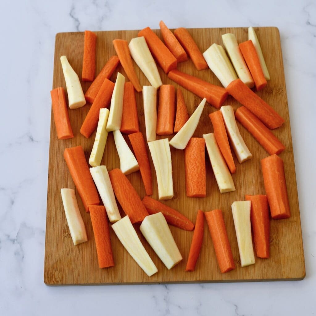 Chopped carrots and parsnips arranged on a wooden cutting board