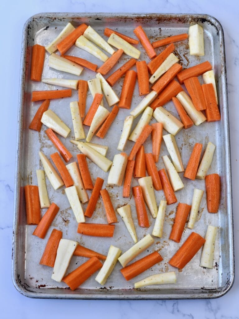 Roasted carrots and parsnips on a metal baking sheet
