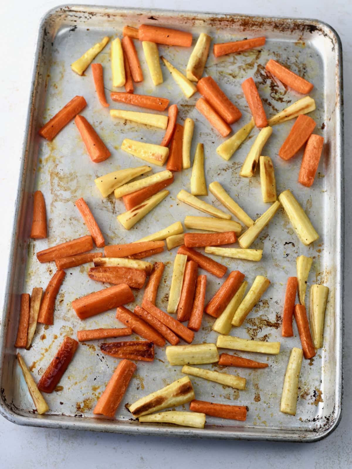 Roasted carrots and parsnips on a metal baking sheet