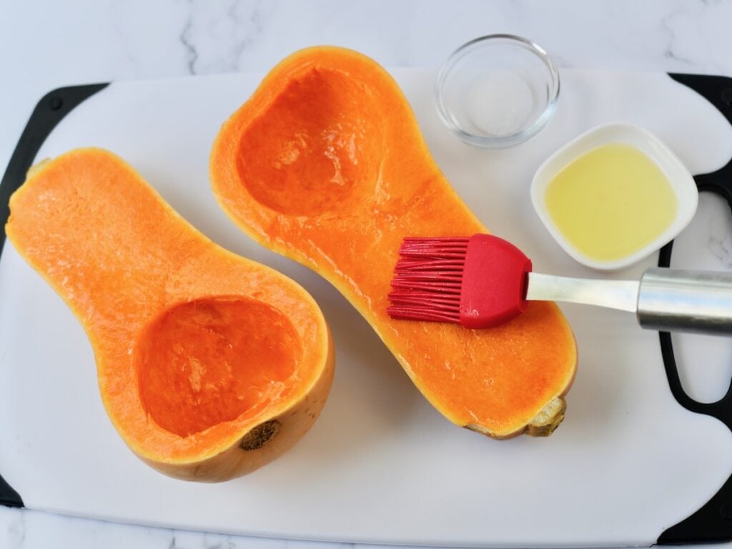 Brushing butternut squash halves with oil