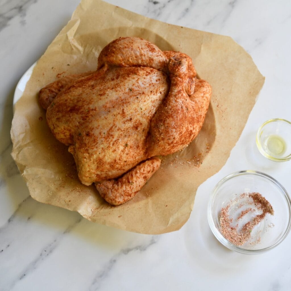 Seasoned raw whole chicken on brown paper
