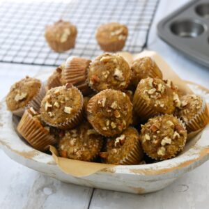 Banana nut bread mini muffins with pecans in white wooden bowl.