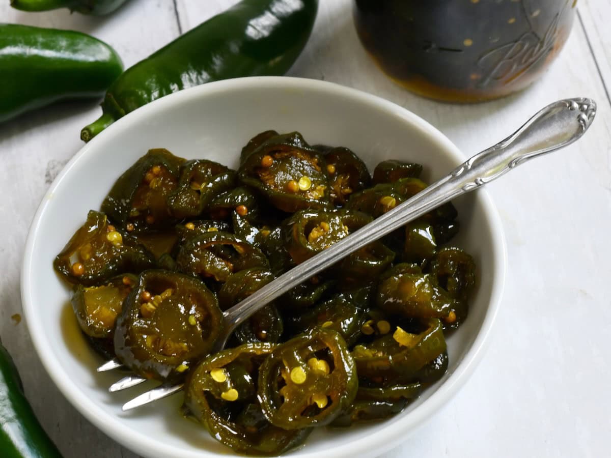 Small white bowl of candied jalapeno peppers.