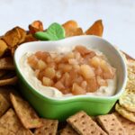 Apple pie dip topped with chopped apple pie filling in a green apple-shaped dish