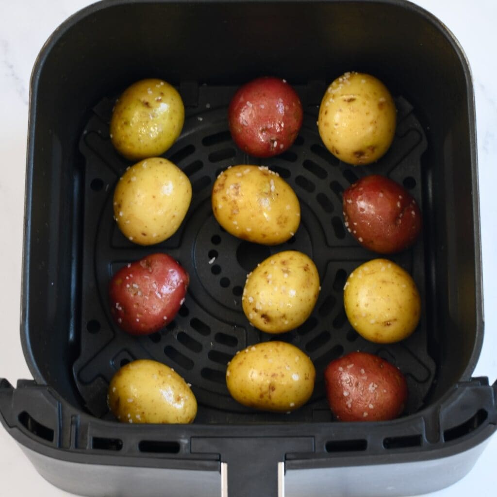 Uncooked potatoes arranged in an air fryer basket