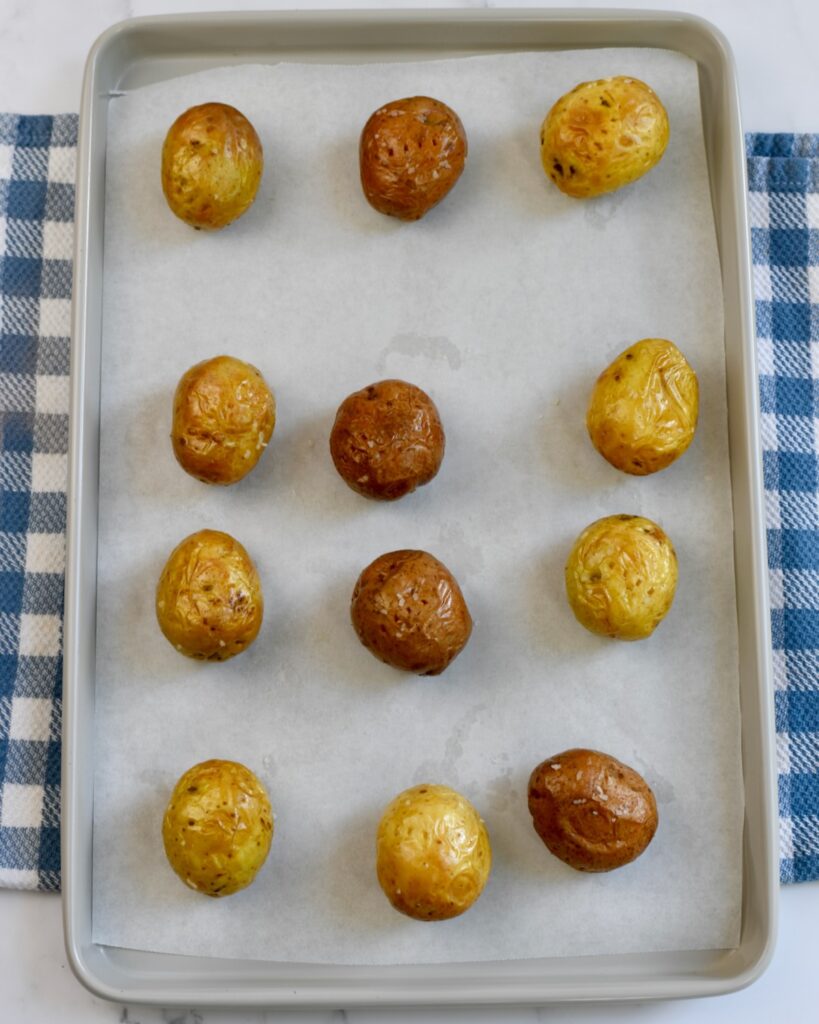 Golden brown mini potatoes baked on a parchment-lined sheet after cooking 
