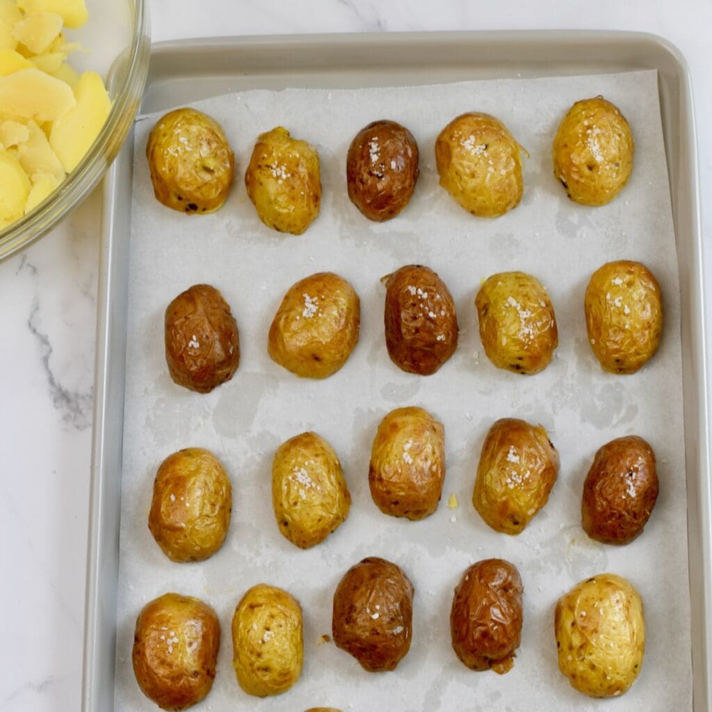 Hollowed-out mini potato skins on a parchment-lined baking sheet