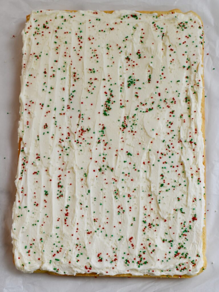 sugar cookie bars covered with white frosting and topped with red and green sprinkles
