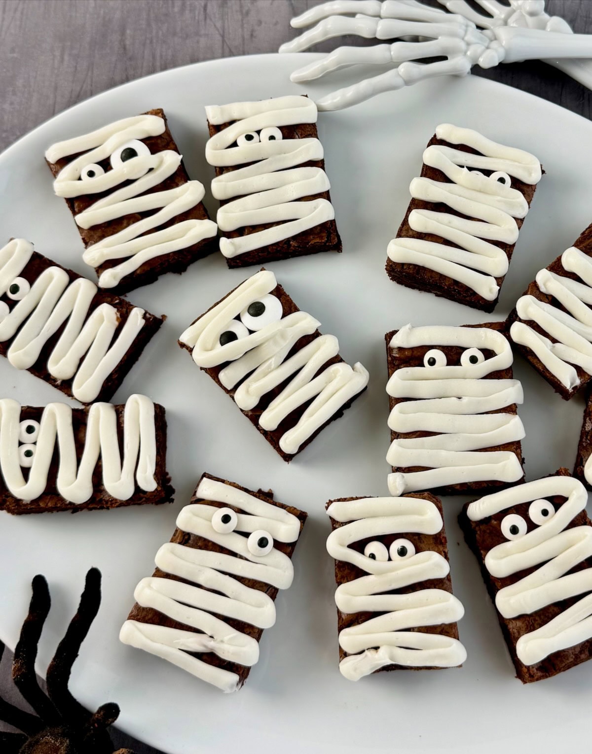 Brownies decorated as mummies on white platter.