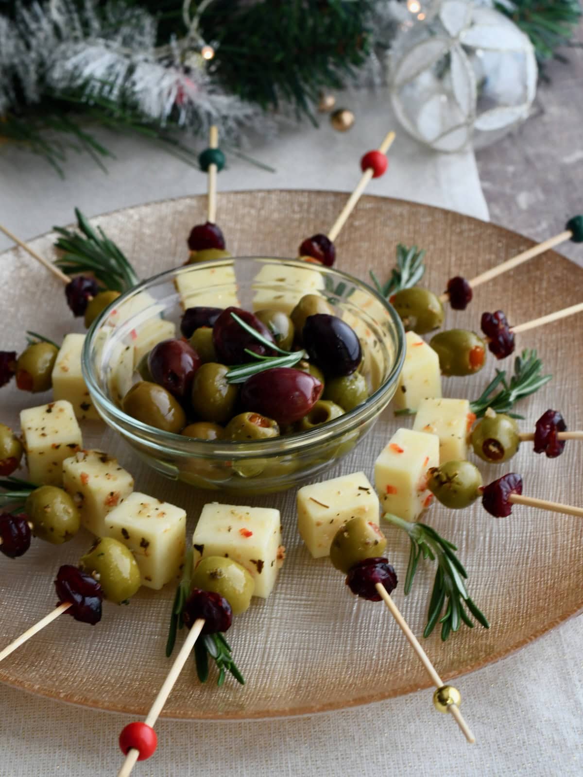 platter of Cranberry Olive Cheese Bites arranged in a circle around a bowl of mixed olives, garnished with fresh rosemary