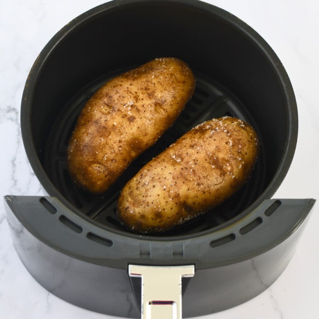 Two russet potatoes placed into the ninja air fryer basket.